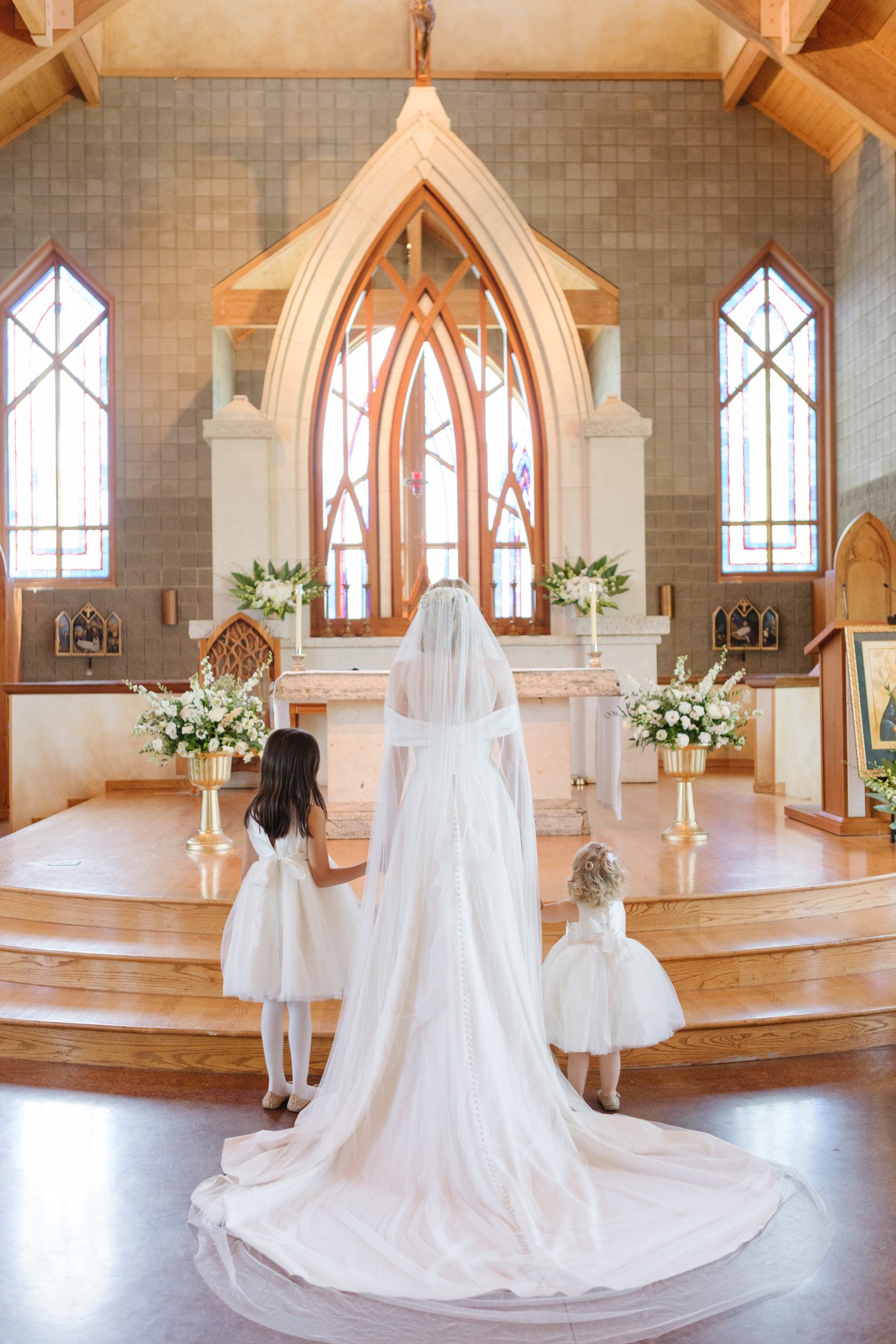 bride with flower girls at wedding alter