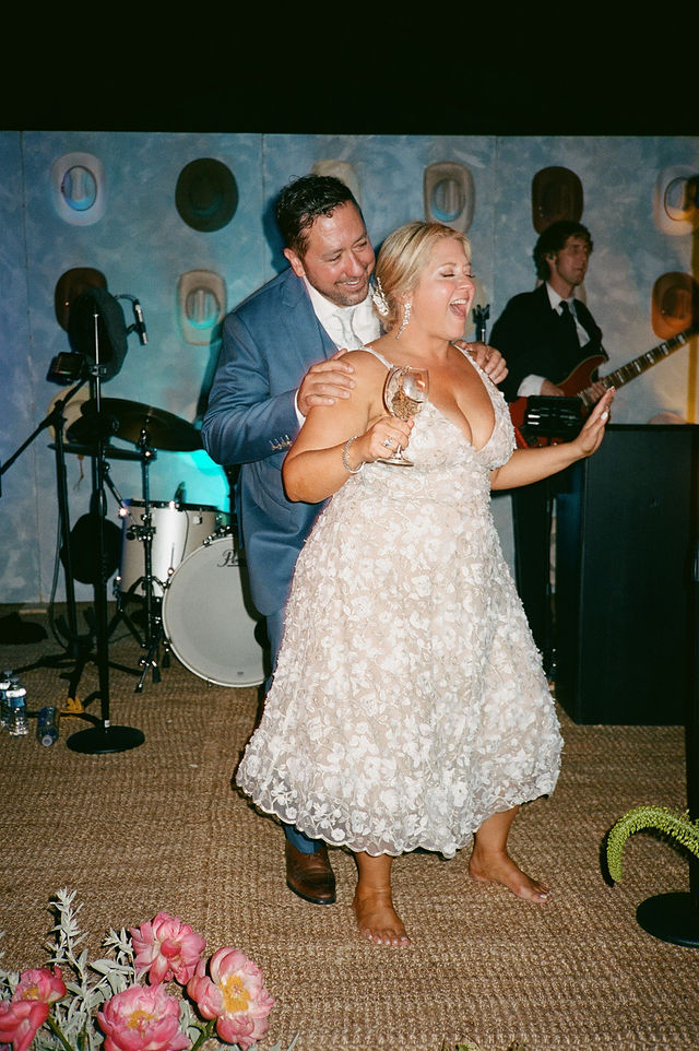 bride dancing and singing barefoot at her western themed summer wedding