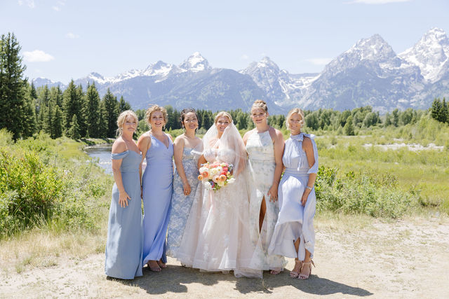 bride and her bridesmaids dressed in a powder blue with mountains in the background