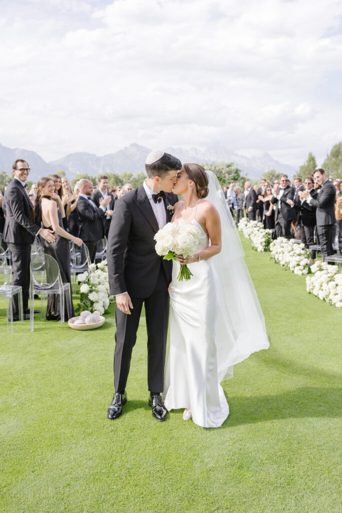 bride and groom kissing for the first time as husband and wife with alpine views in the background