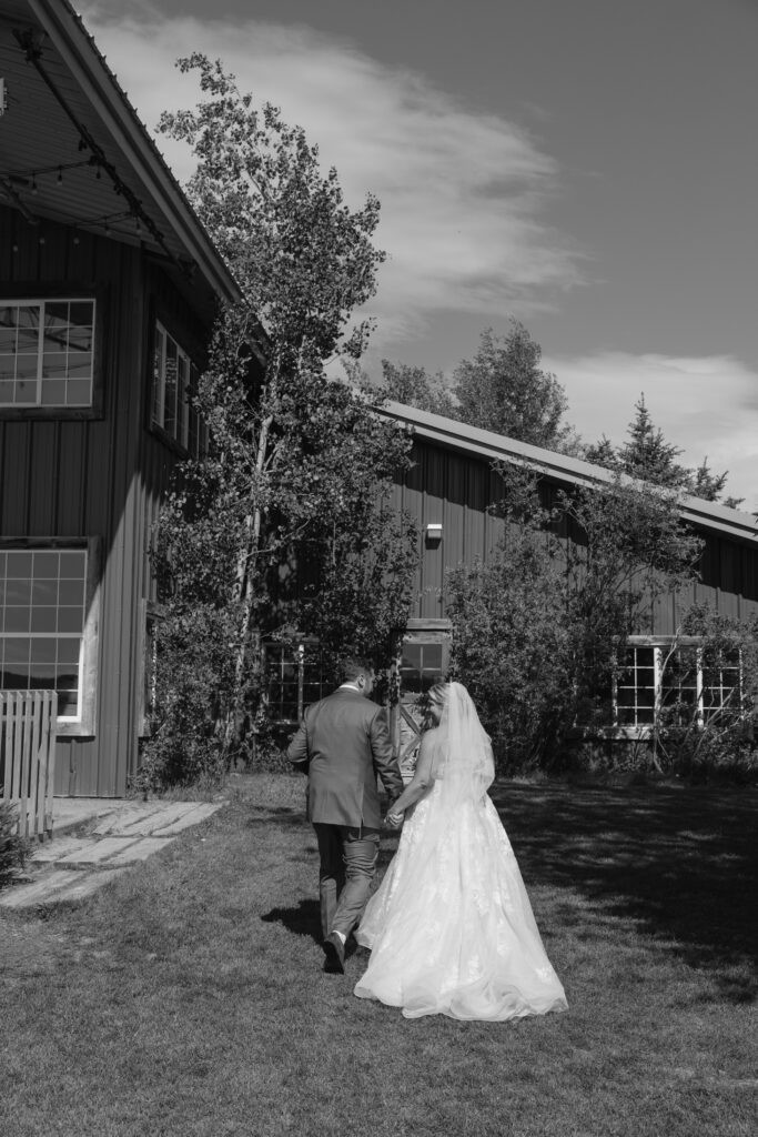 black and white photo of the bride and groom walking up to the barn at Diamond Cross Ranch