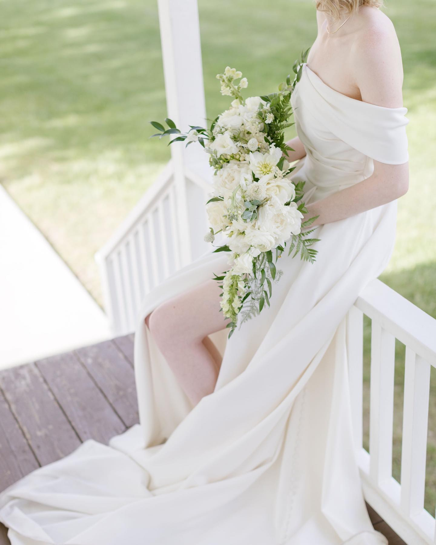 bride sitting on the railing with her stunning bouquet 