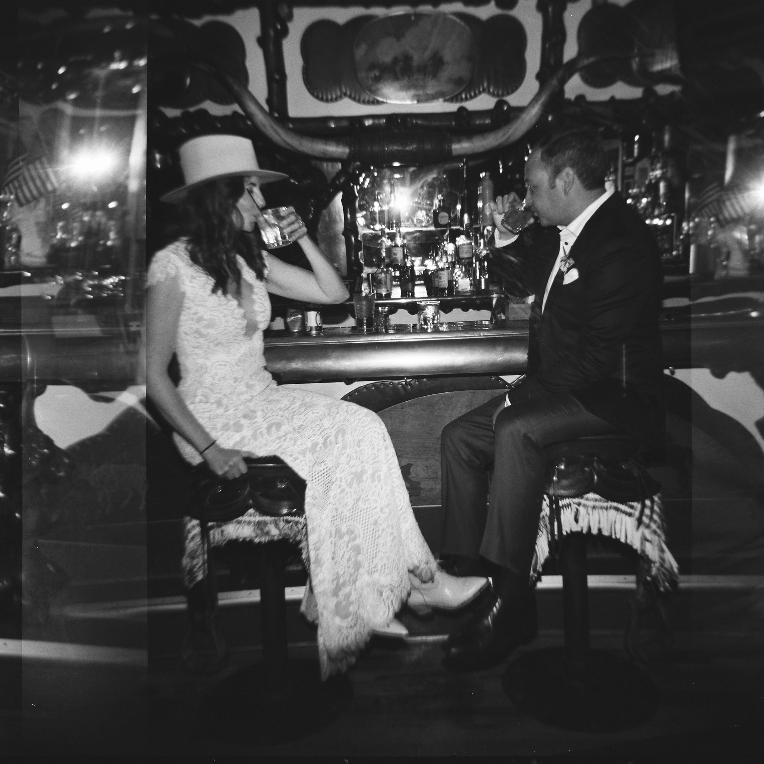 black and white photo of bride and groom sitting on the saddle stools