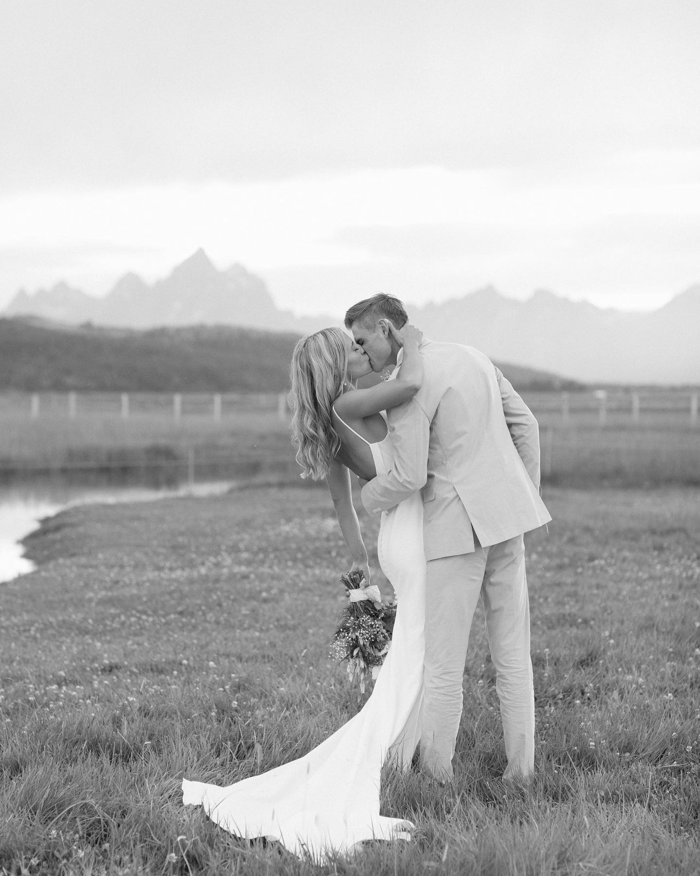 eloping-in-jackson-hole a couple kissing on their wedding day in a black and white photo with mountains in the background
