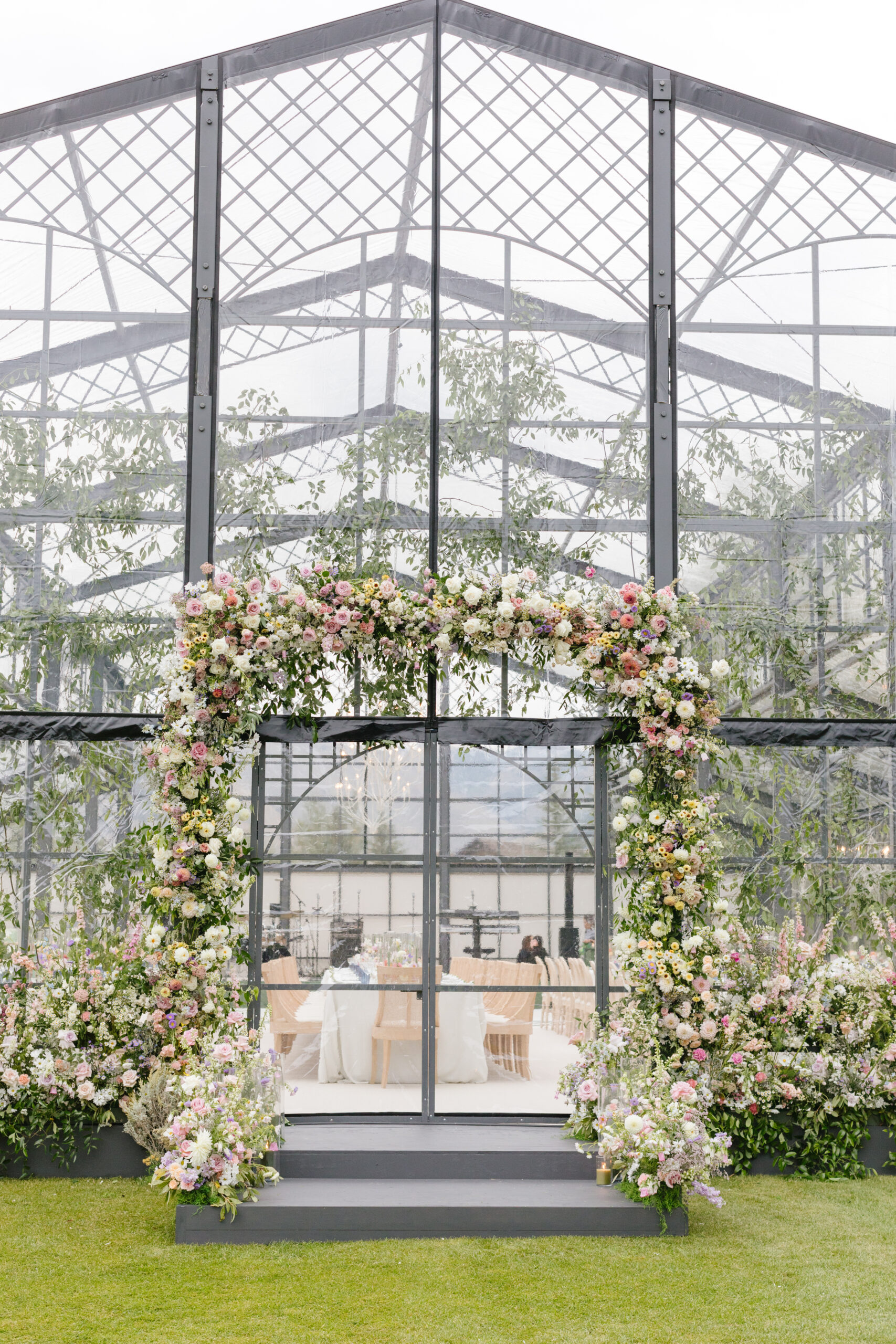 stunning glass wedding reception venue with a floral archway