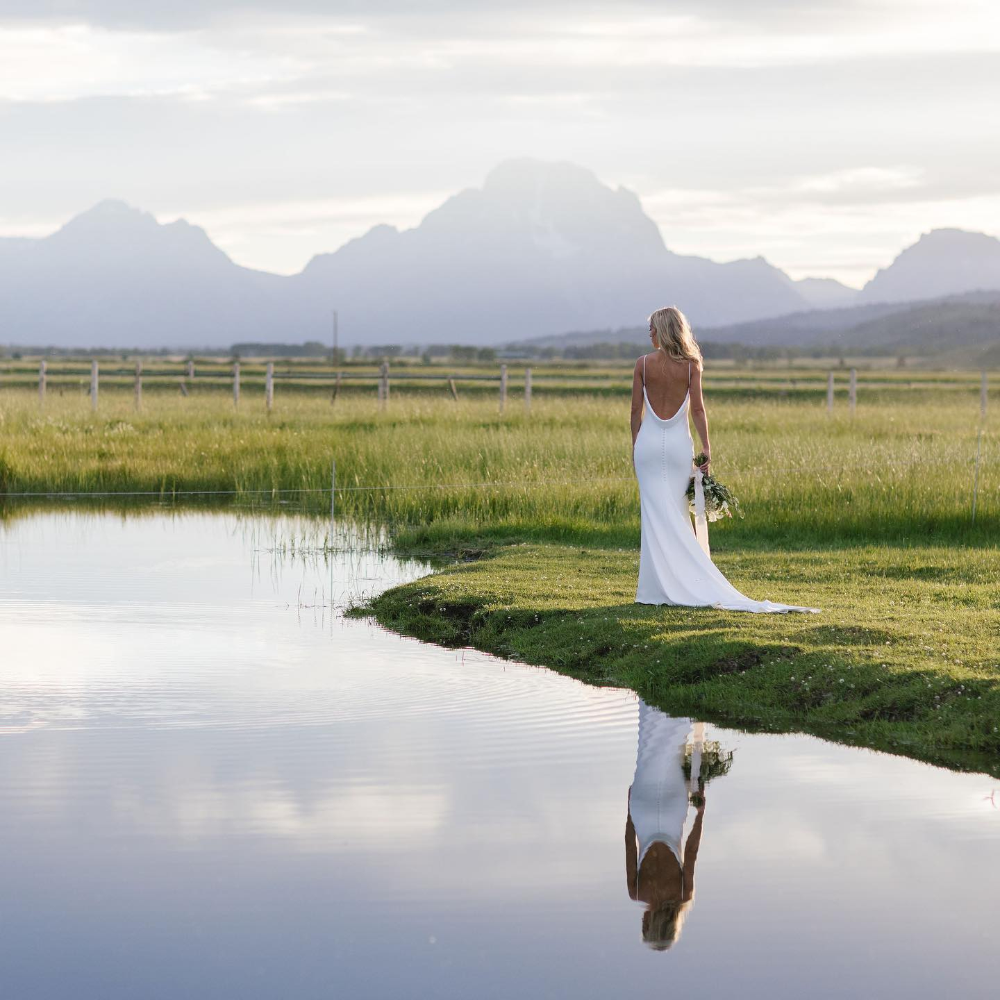 bride standing by the water looking out towards the mountains