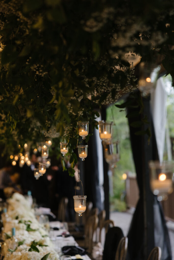 Romantic candlelit reception at Jackson Hole Golf and Tennis Club with hanging votives and lush florals.