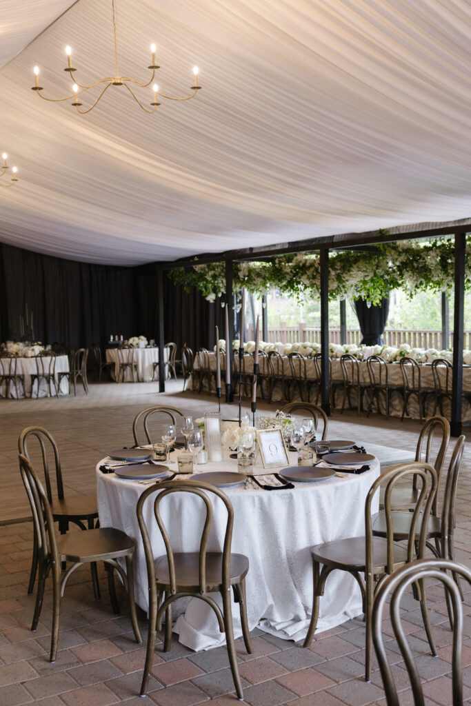 Romantic tented reception space with soft draping, candlelit tables, and elegant greenery hanging above.