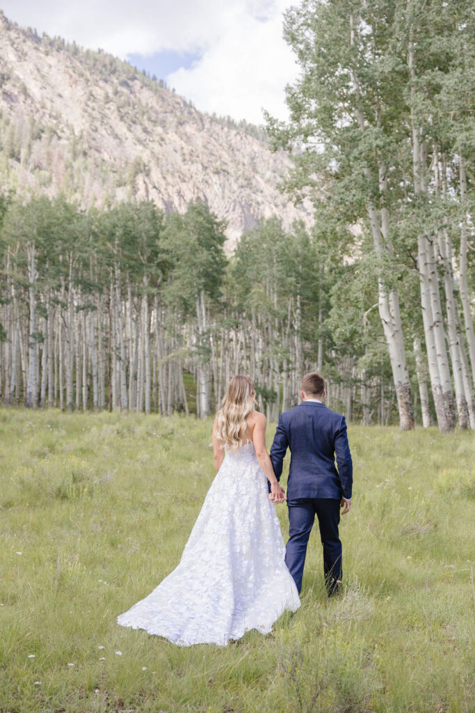 Couple walks through forest after exchanging vows in one of the best places to elope, Grand Teton National Park.