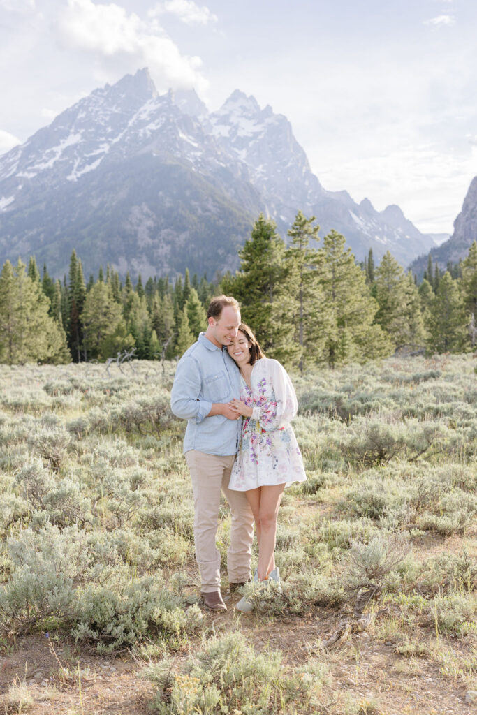 Couple poses for photo in GTNP with dramatic view of mountain behind them