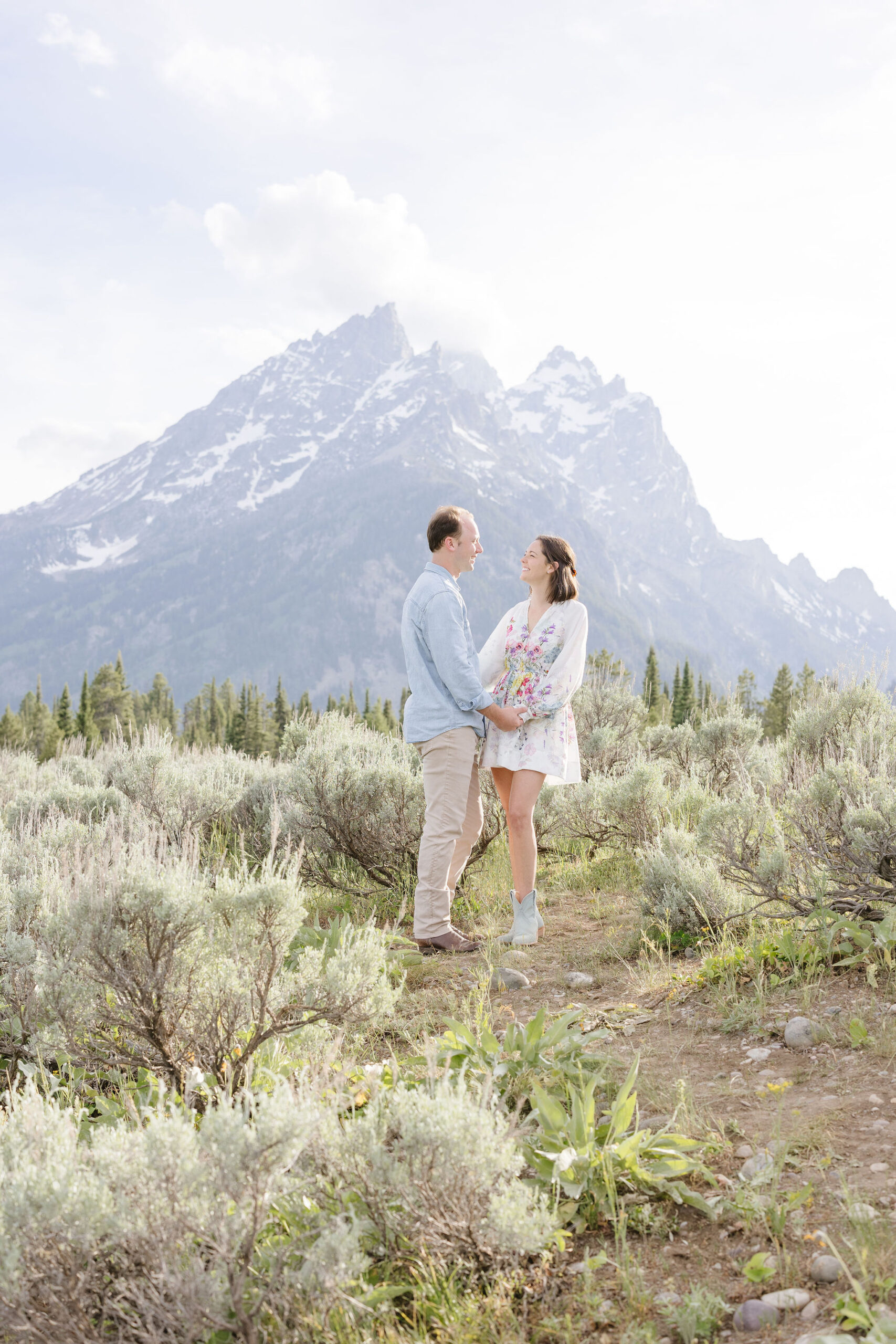 Couple get engagement photos in GTNP with a view of a mountain behind them.