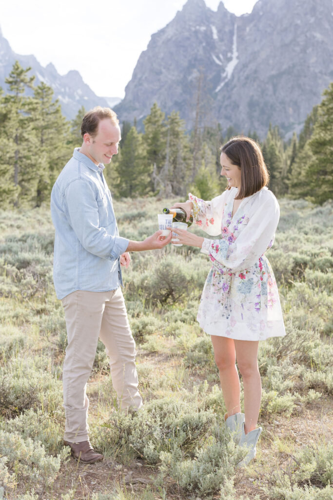 Couple popping champagne during engagement photos in GTNP.