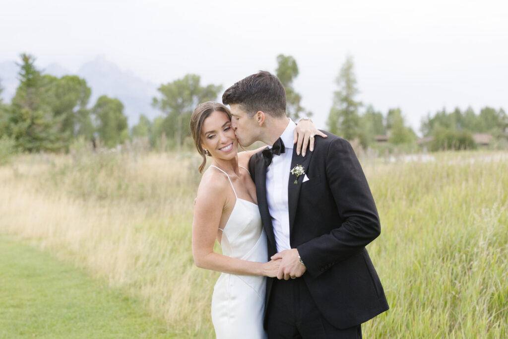 Bride and groom pose for photo outside of their indoor reception venues in Jackson Hole and Grand Teton.