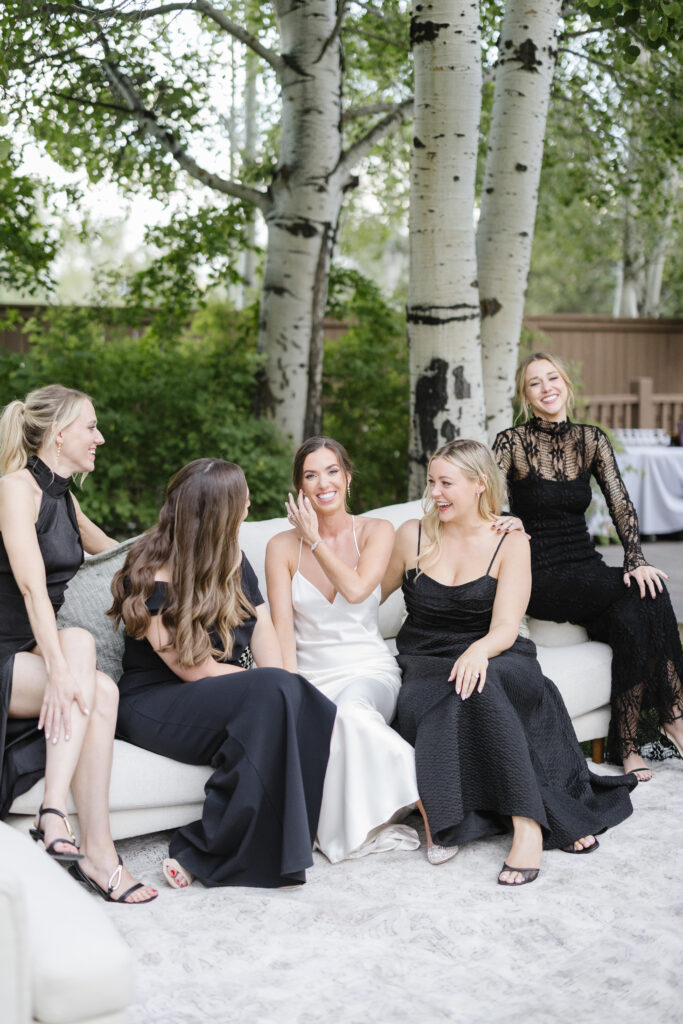 Bride and bridal party sit together on lounge furniture at indoor reception venues in Jackson Hole and Grand Teton.