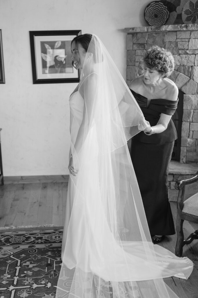 Catholic wedding photographer captures mom helping adjust brides gown. 