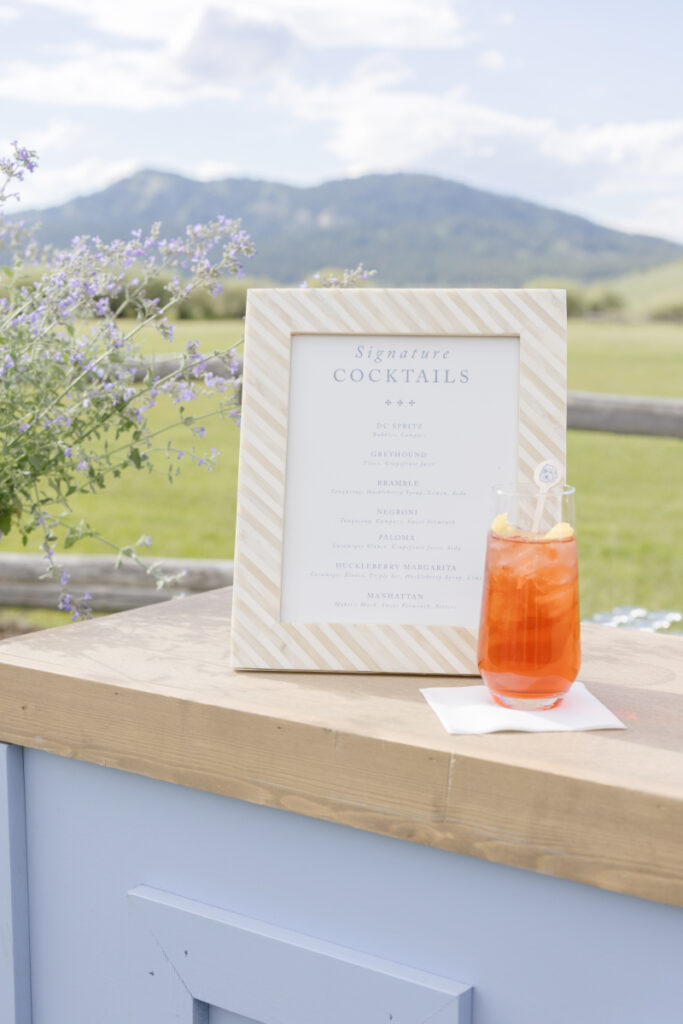 Signature cocktail sitting next to sign at Wyoming reception in the Tetons.