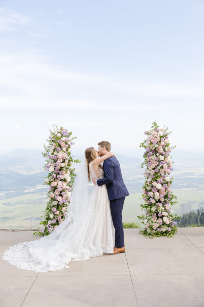 Bride and groom share first kiss during ceremony at a beautiful Wyoming wedding location.