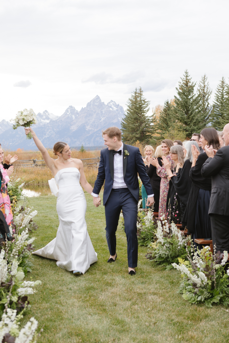 Couple exits ceremony at one of the most beautiful Wyoming wedding locations with mountain views.