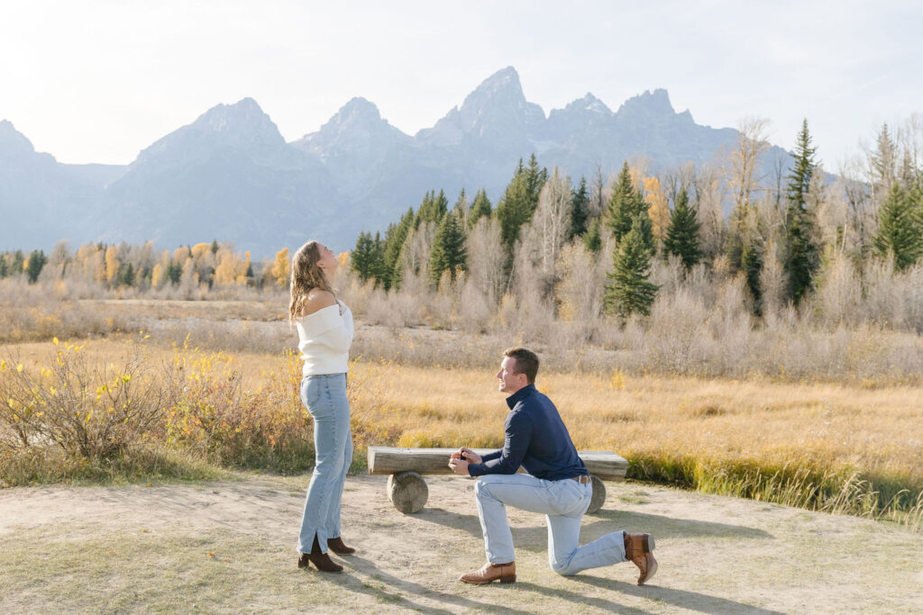 Man gets down on one knee in one of the best places to propose in Jackson Hole, surprising his girlfriend with breathtaking mountain views in the background.