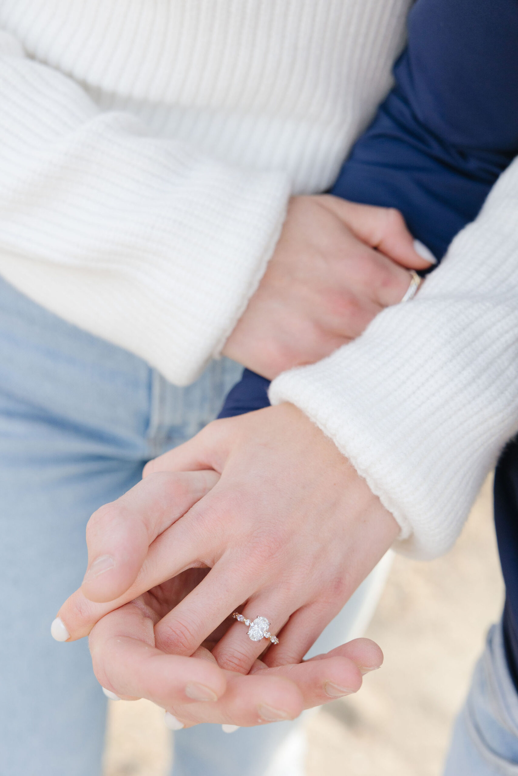 Photographer captures close up of newly engaged couple holding hands, showing off the ring.