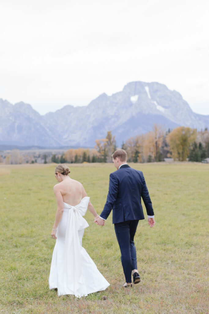 Jackson Hole elopement photographer captures bride and groom walking together holding hands.