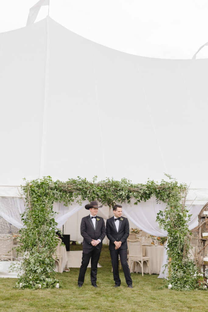 Two ushers standing at entrance of reception tent waiting to seat guests.