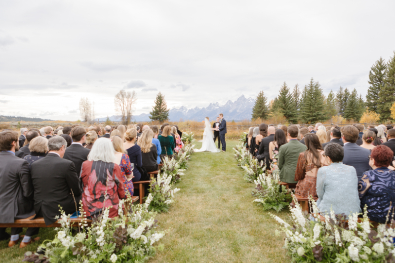Bride and groom exchange vows with breathtaking views of the Tetons Rendezvous Peak towering behind them at their Moose Creek Ranch wedding.
