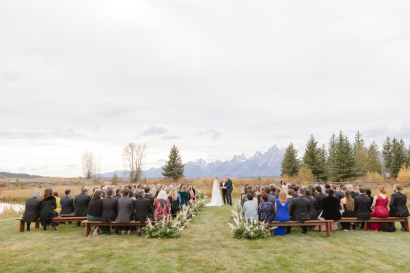 Bride and groom exchange vows with breathtaking views of the Tetons Rendezvous Peak towering behind them at their Moose Creek Ranch wedding.