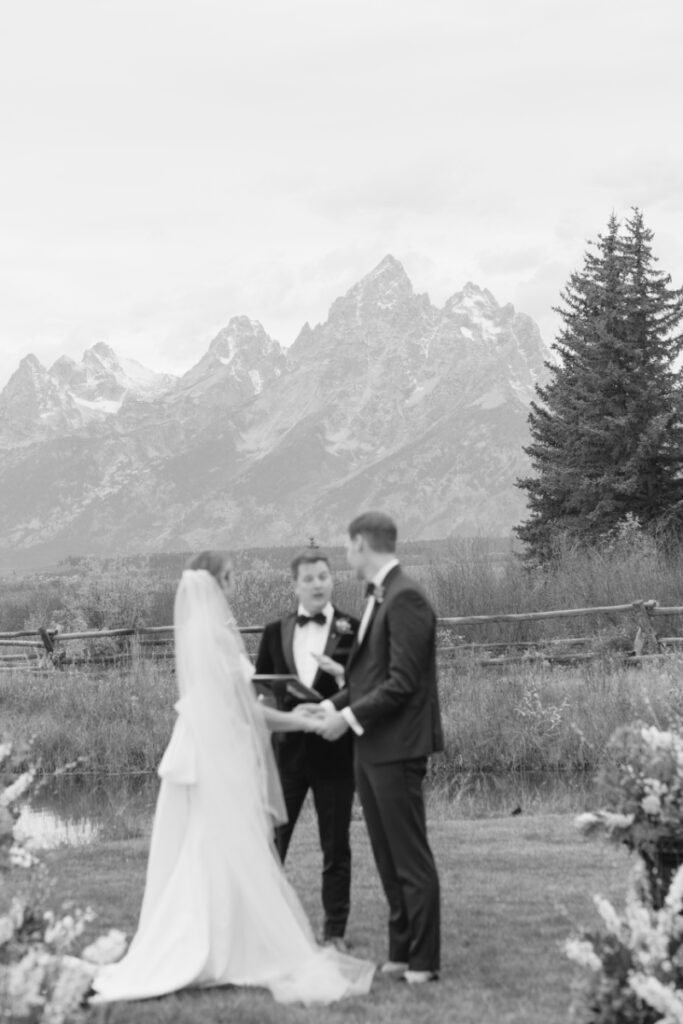 Black and white photo of the view of the Rendezvous Peak behind a bride and groom exchanging vows.