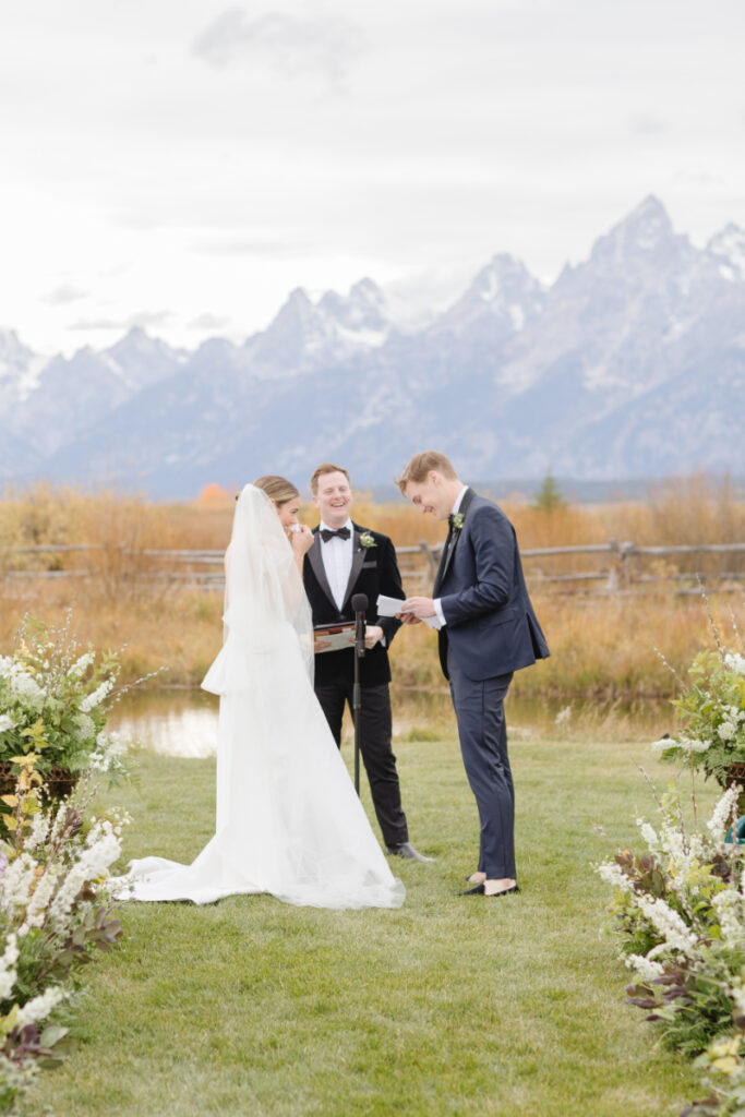 Bride and groom exchange vows with breathtaking views of the Tetons Rendezvous Peak towering behind them at their Moose Creek Ranch wedding.