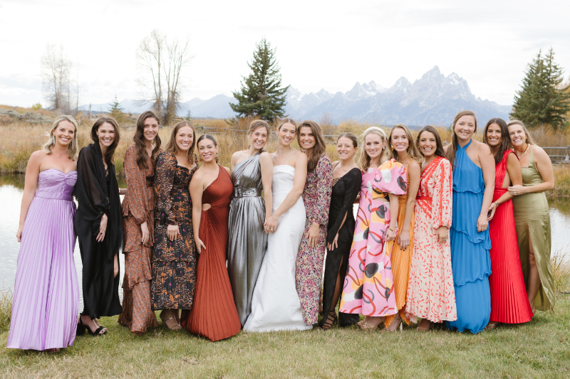 Bride poses with group of her girlfriends with view of the Tetons behind them.