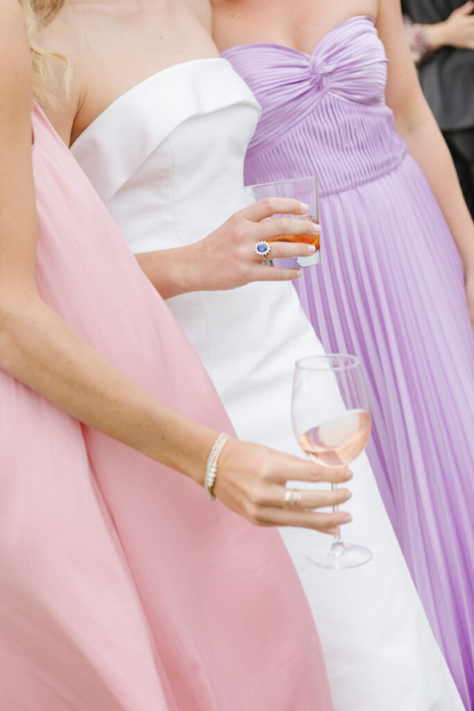 Close up shot of bride and bridesmaids holding signature drinks and wine during cocktail hour at a Moose Creek Ranch wedding.