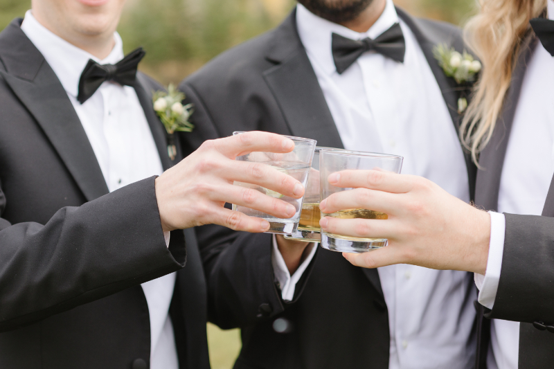 Close up shot of groom and groomsmen toasting with bourbon.