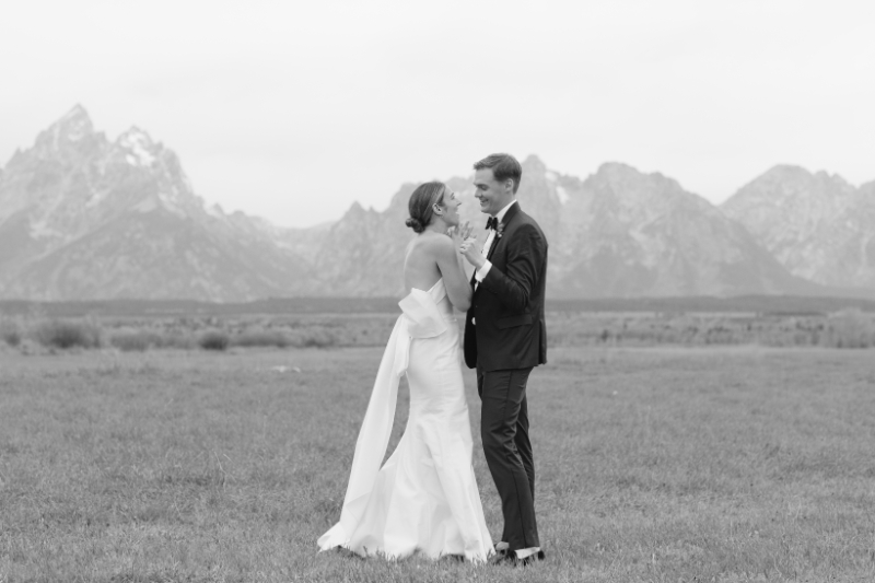 Black and white photo of bride and groom with sweeping views of the Tetons behind them.