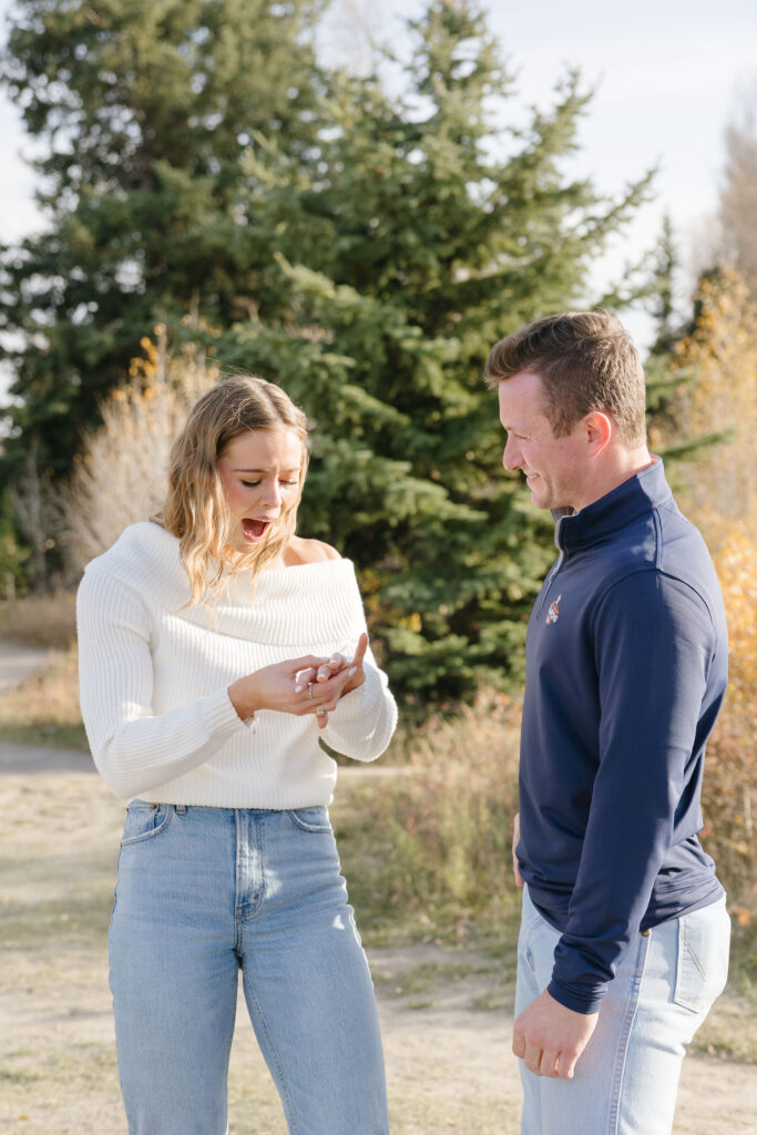 Girl looks at engagement ring with excitement during cowboy engagement photoshoot