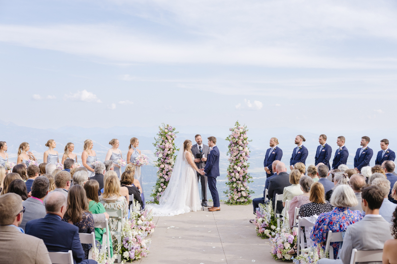 Bride and groom stand surrounded by their friends and family on top of their gorgeous destination wedding venue ceremony site.