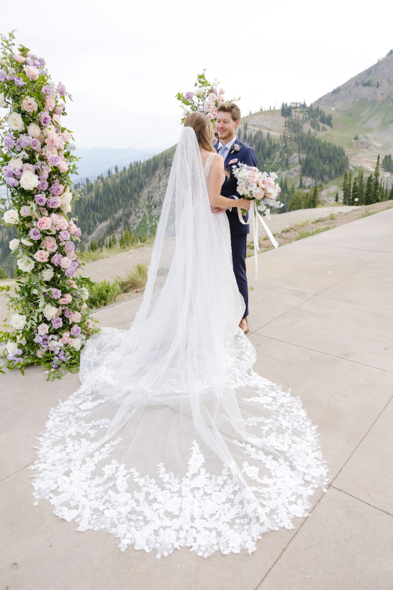 Bride and groom stand at ceremony site, surrounded by mountain views.