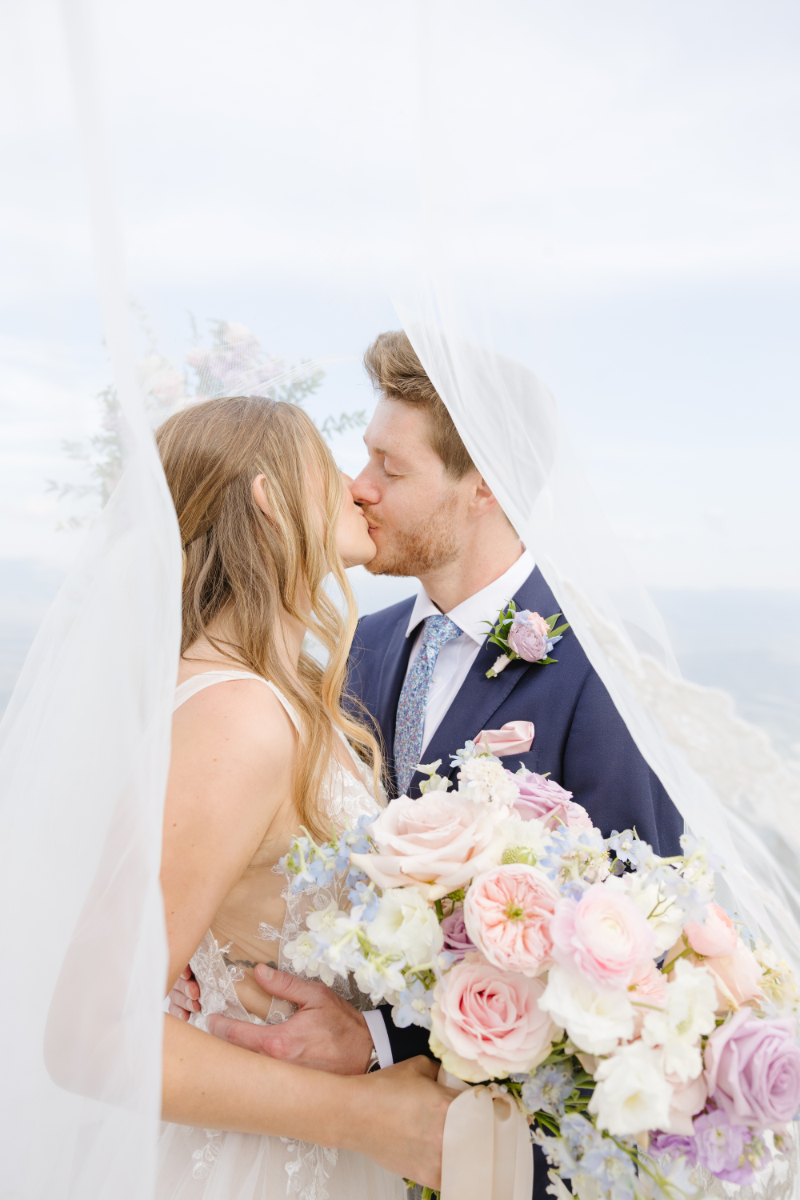 Bride and groom kiss underneath brides veil while taking portraits at Hotel Yellowstone at Jackson Hole.
