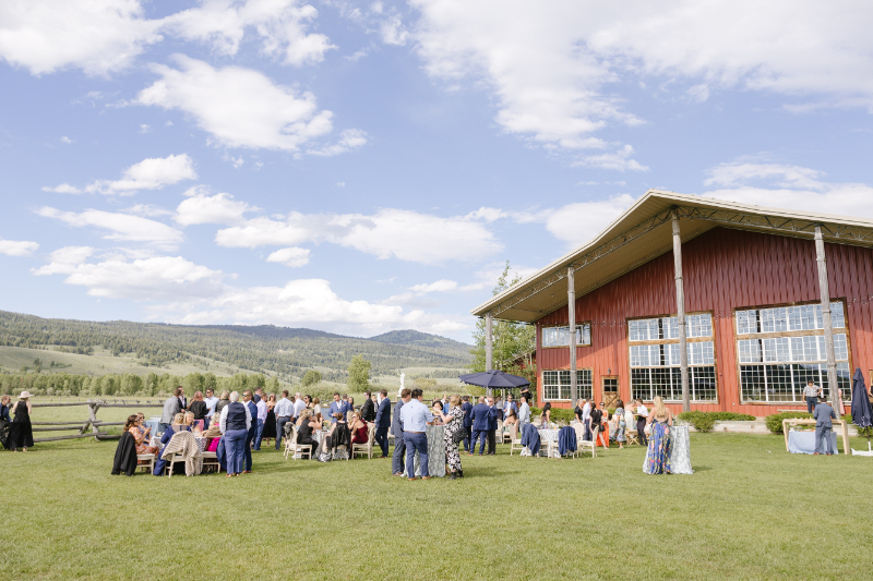 Wedding guests sit on lawn during cocktail hour. 