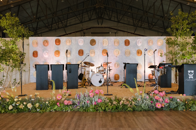 Stage set with band equipment, with a cowboy hat installation wall as the backdrop. 