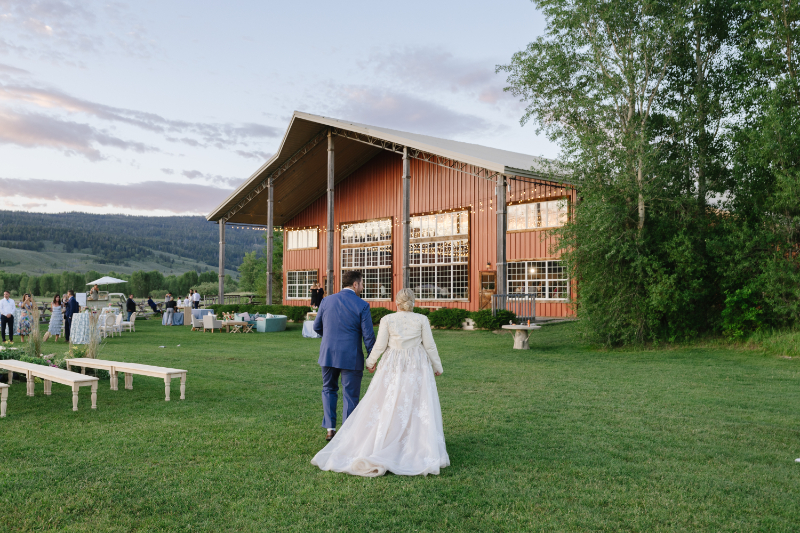 Bride and groom walk hand and hand as they stroll together toward their multi-day wedding venue in Jackson Hole.