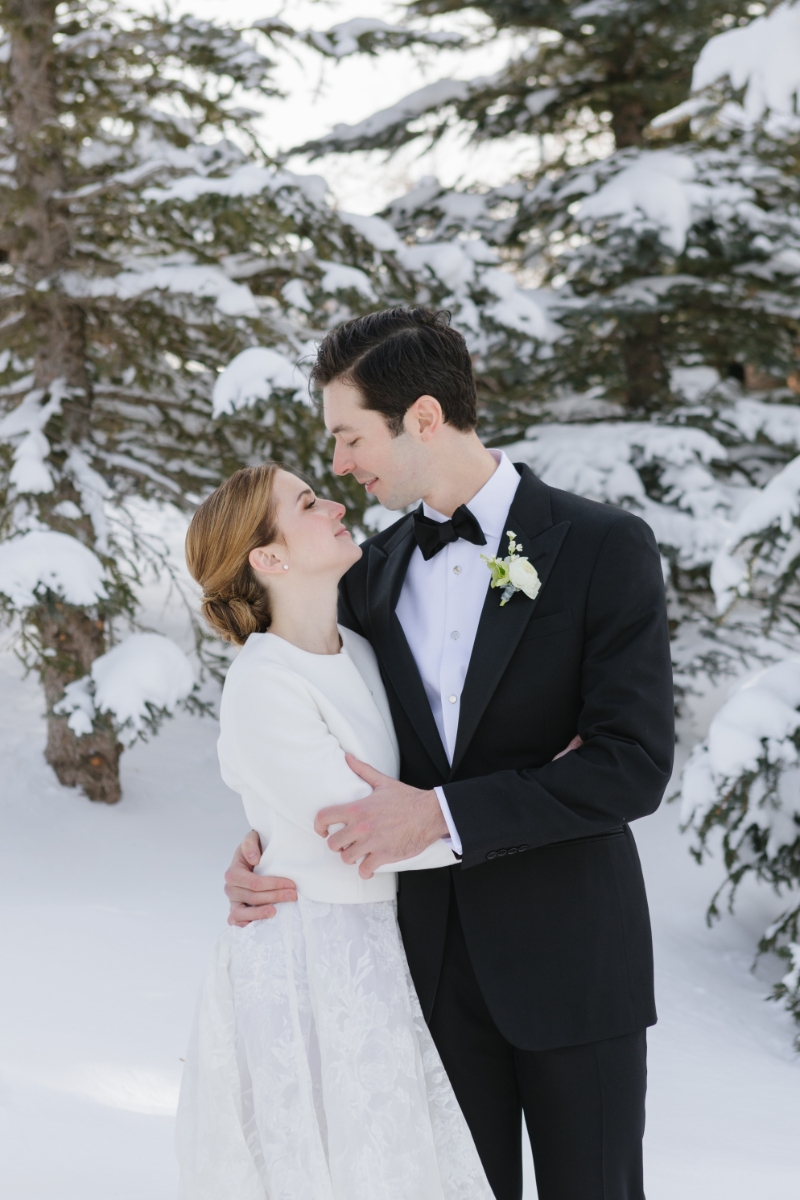 Bride and groom kiss while snow falls around them during their winter elopement in Jackson Hole.
