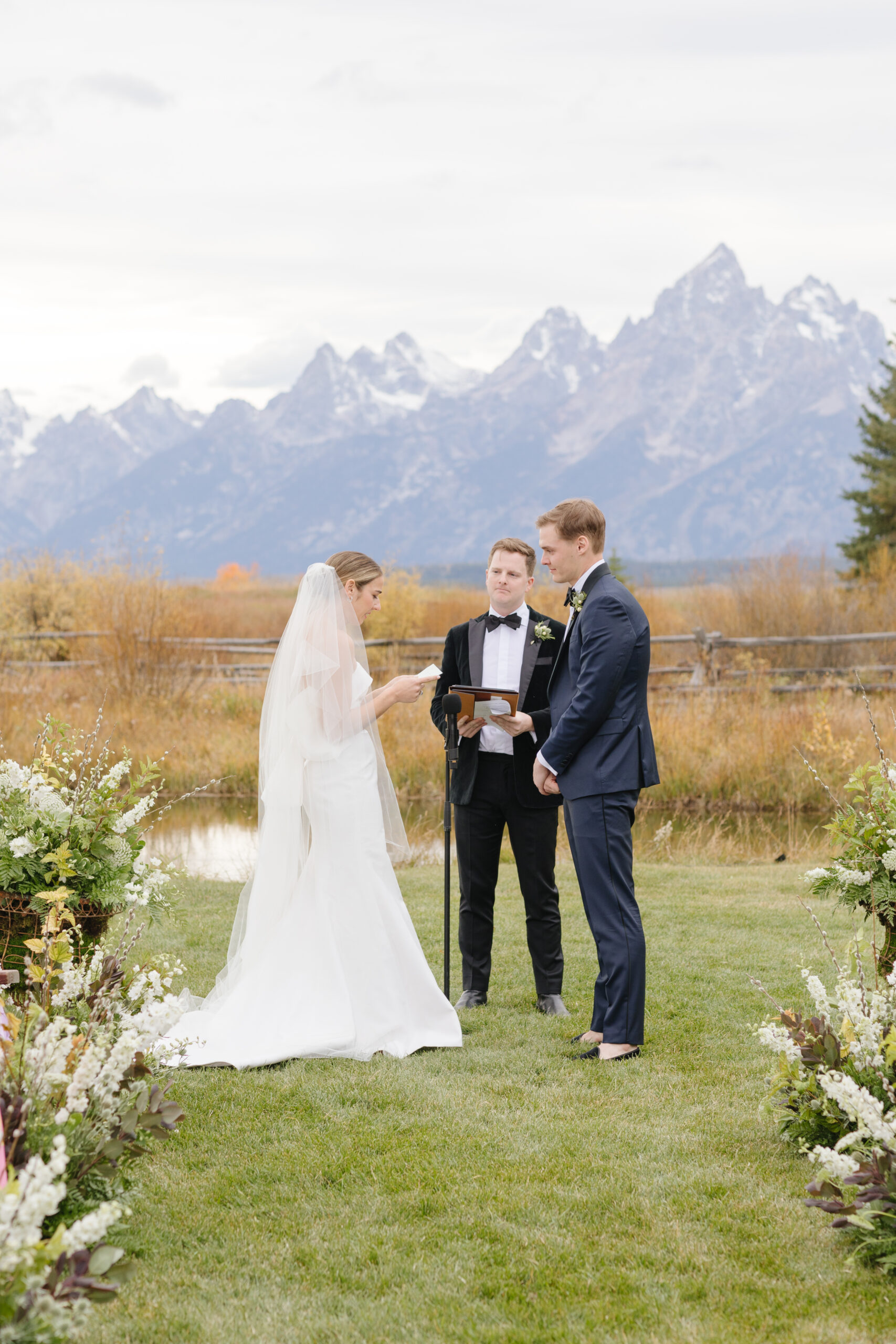 Bride and groom exchange vows during wedding ceremony with the Grand Teton mountains behind them.