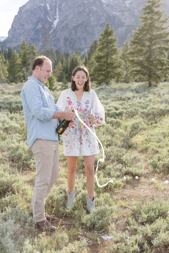 Couple opening up champagne bottle and celebrating there engagement with a photo shoot.