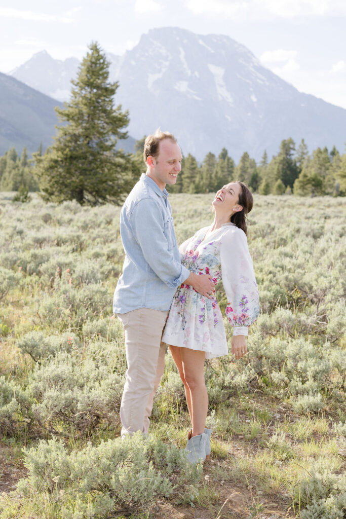 Husband-to-be holding his wife-to-be on the hip as she leans back with a big smile on her face for their engagement photography.
