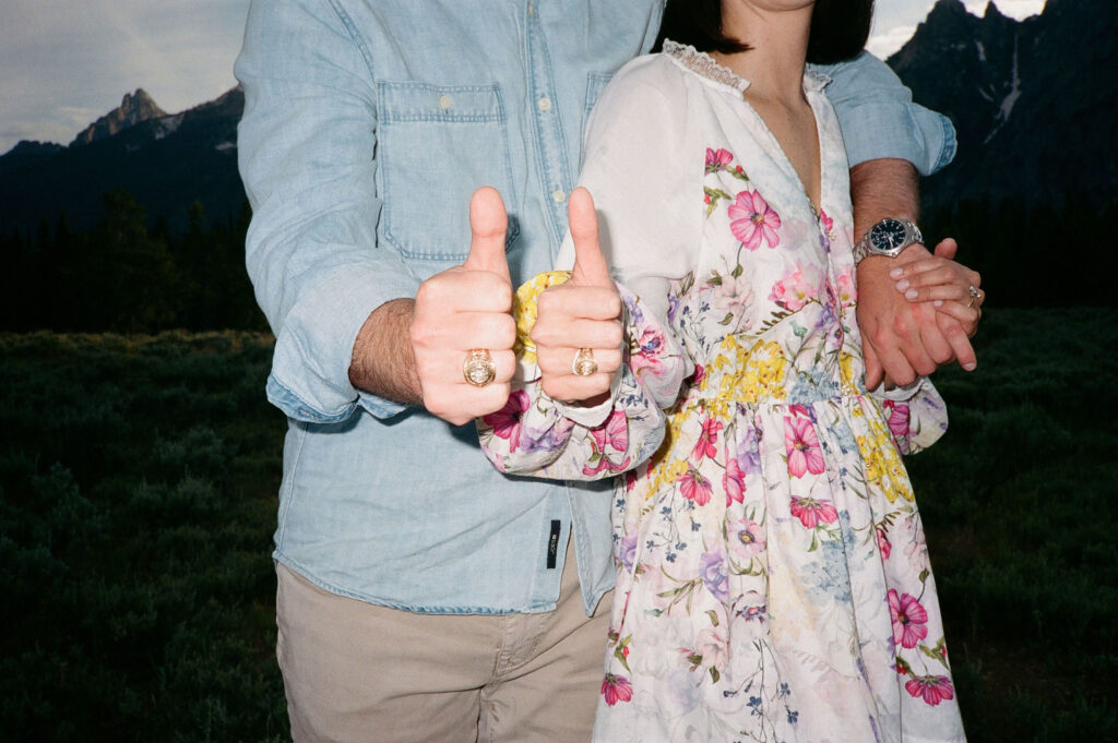 Couple thumps up with their rings to showcase their engagement at Jackson Hole with a film photo.