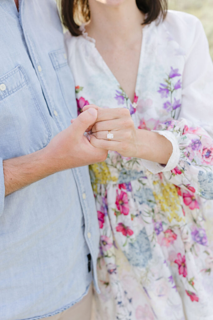 couple holding each other hands as the lady showcases her ring for her engagement photography.