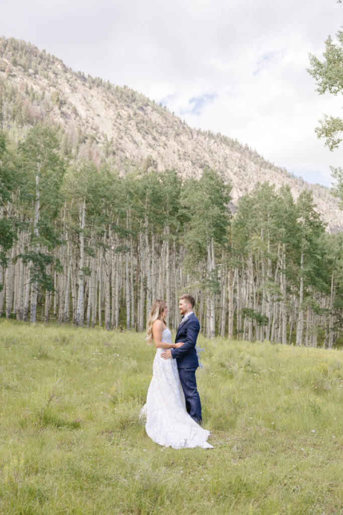 Bride and groom stand together in an open field surrounded by birch trees in Yellowstone National Park.