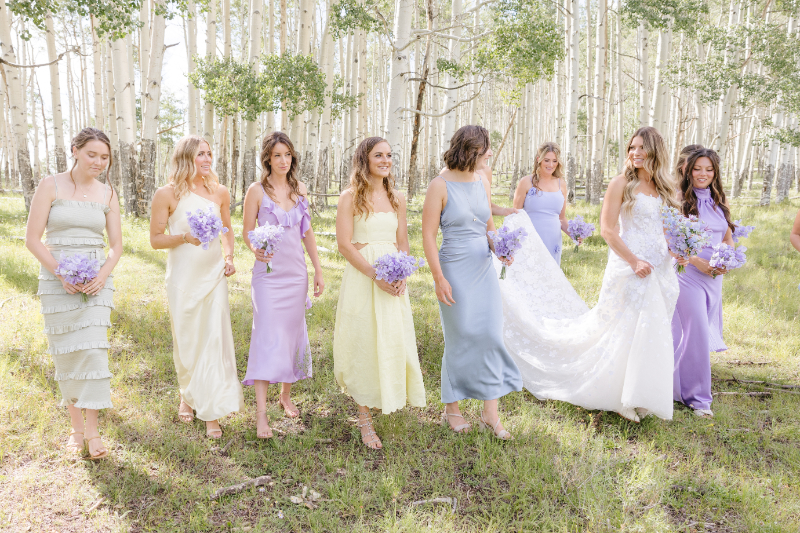 Bride and bridesmaids at Yellowstone National Park. Bride in white and bridesmaid in pastel color dresses.
