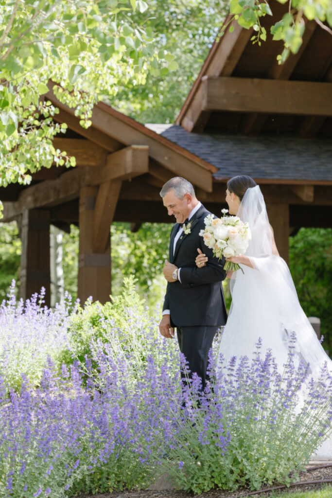 Bride walking with father through a garden setting during a Grand Teton wedding